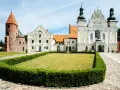 Kamienne kolumny w strzelnie otaczają trawnik przed barokowym kościołem i romańską wieżą.