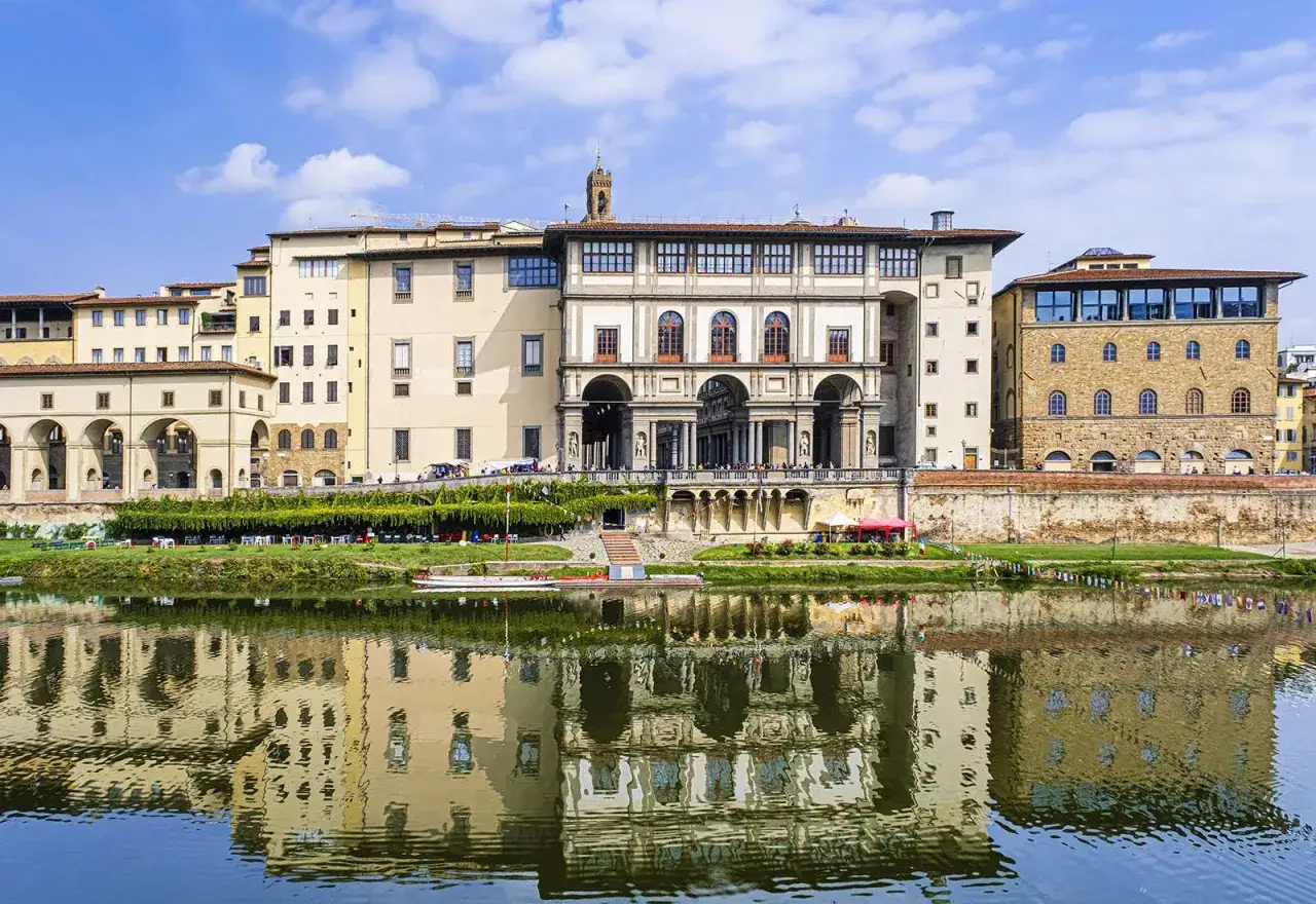 Florenckie muzeum Uffizi z arkadami i wieżą, odbijające się w rzece Arno.