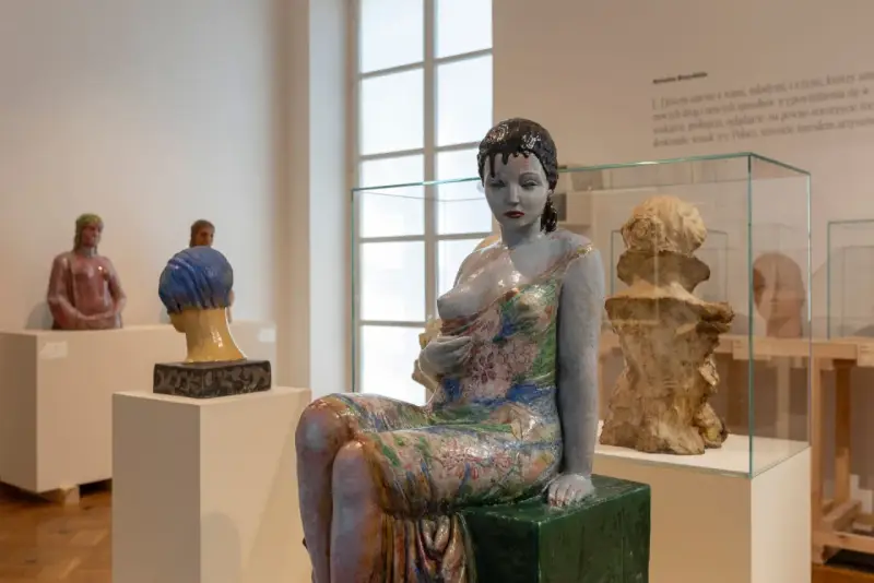 Ceramiczna rzeźba kobiety w kwiecistej sukni, dzieło inspirowane twórczością Olgi Niewskiej, prezentowana w muzeum.